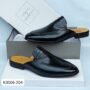 A pair of black leather moccasin shoes with crocodile embossed detail, displayed on top of a shoe box.
