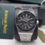Audemars Piguet luxury watch with black face and silver band, presented in a box and accompanied by brand documentation.