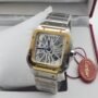 A luxurious Cartier watch with a stainless steel and gold band, displayed in an open box with a red tag, showcasing its transparent face and intricate mechanical movement.