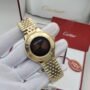 A gold Cartier watch with a black face, displayed on a gloved hand, showcasing its elegant design and luxurious appeal.