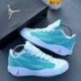 A pair of teal and white sneakers with red Jumpman logos, accompanied by a black shoe box and a small toy hamster.