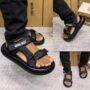 A stylish pair of black sandals with double straps and thick soles, worn by a model showcasing the shoe's comfort and luxury appeal.